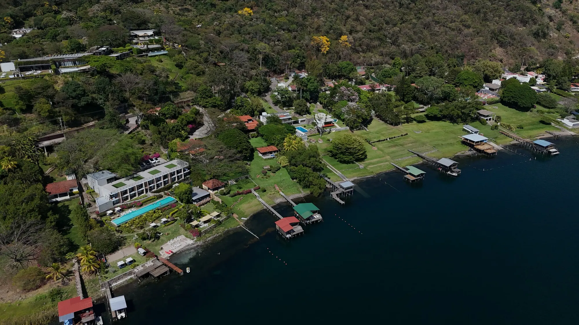 Aerial view of the shoreline of Lago de Coatepeque, lined with houses, hotels and private docks