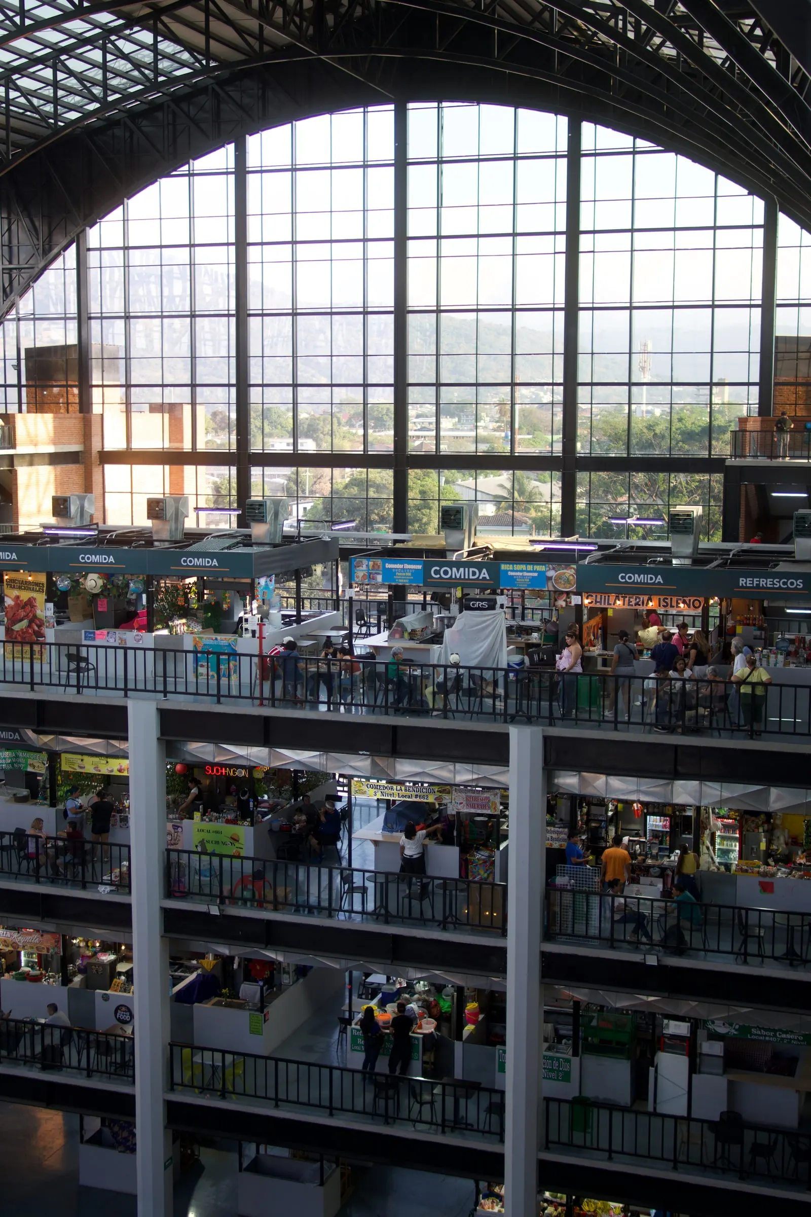 The interior of Mercado San Miguelito in San Salvador, with food stalls on several levels under an arched glass roof